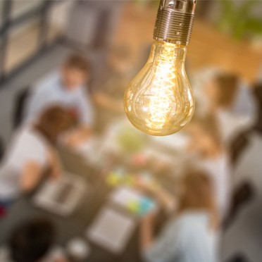 Lampadina illuminata che rischiara un gruppo di persone sedute insieme in un ambiente accogliente